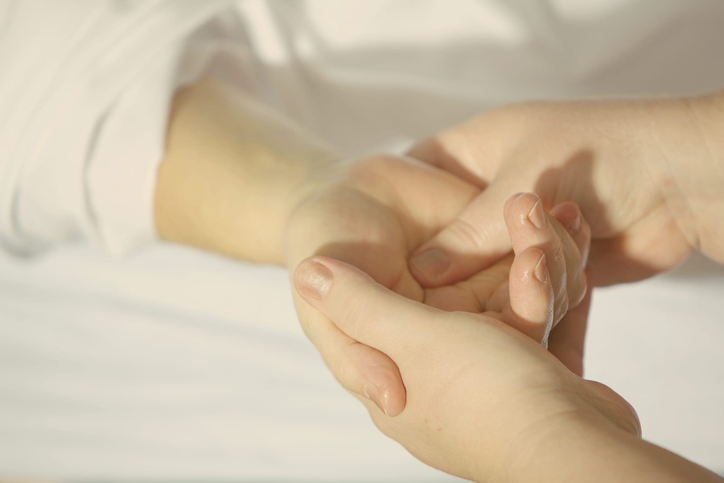A caregiver's hands gently holding a patient's hand