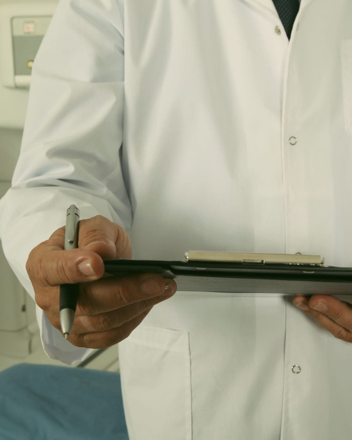 A pediatrician in a white coat holding a clipboard
