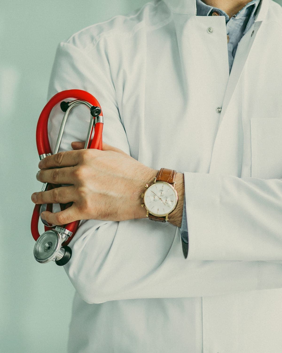 An urgent-care physician in a white coat holding a red stethoscope