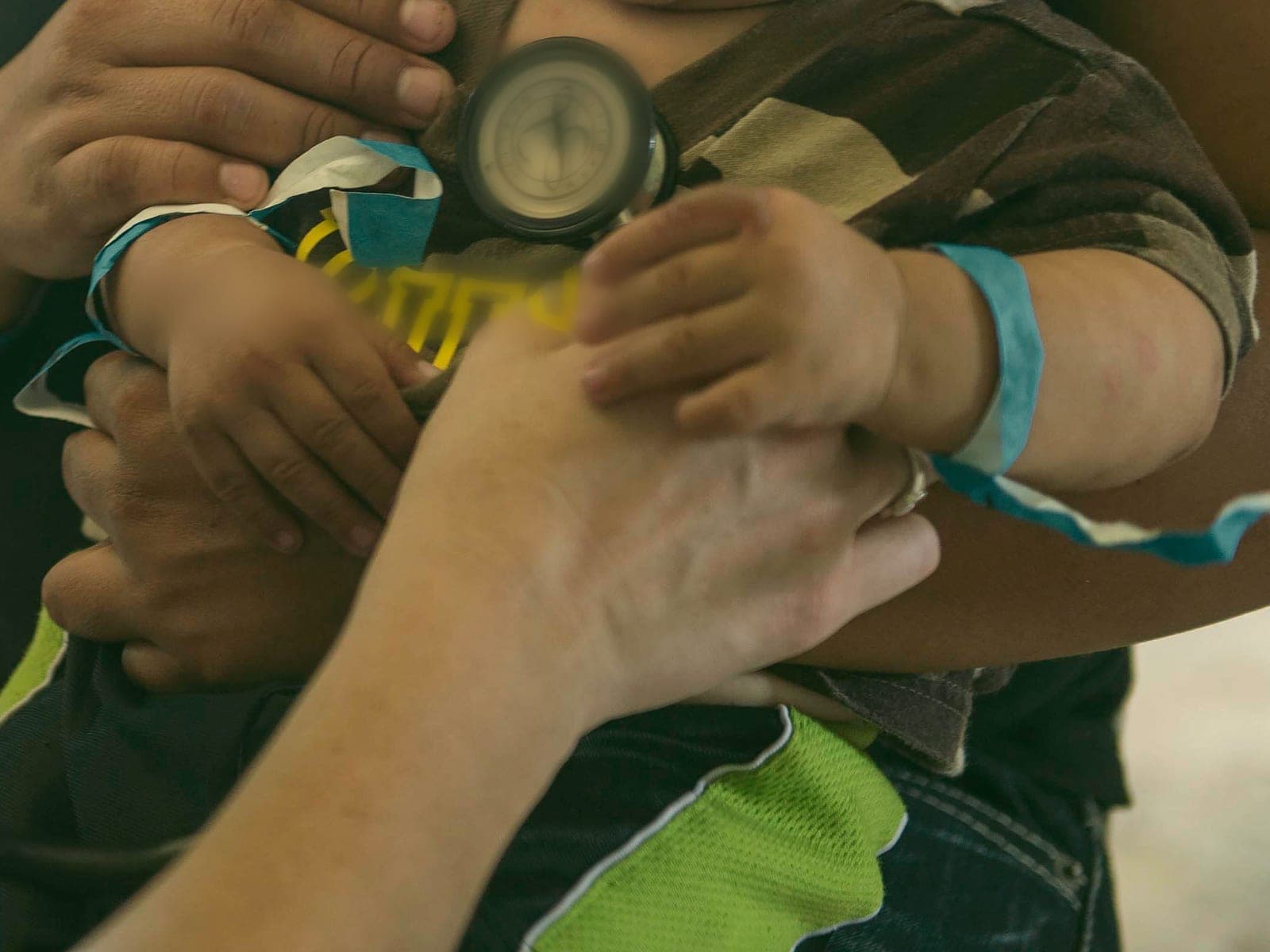 A clinician listening to a toddler's chest with a stethoscope