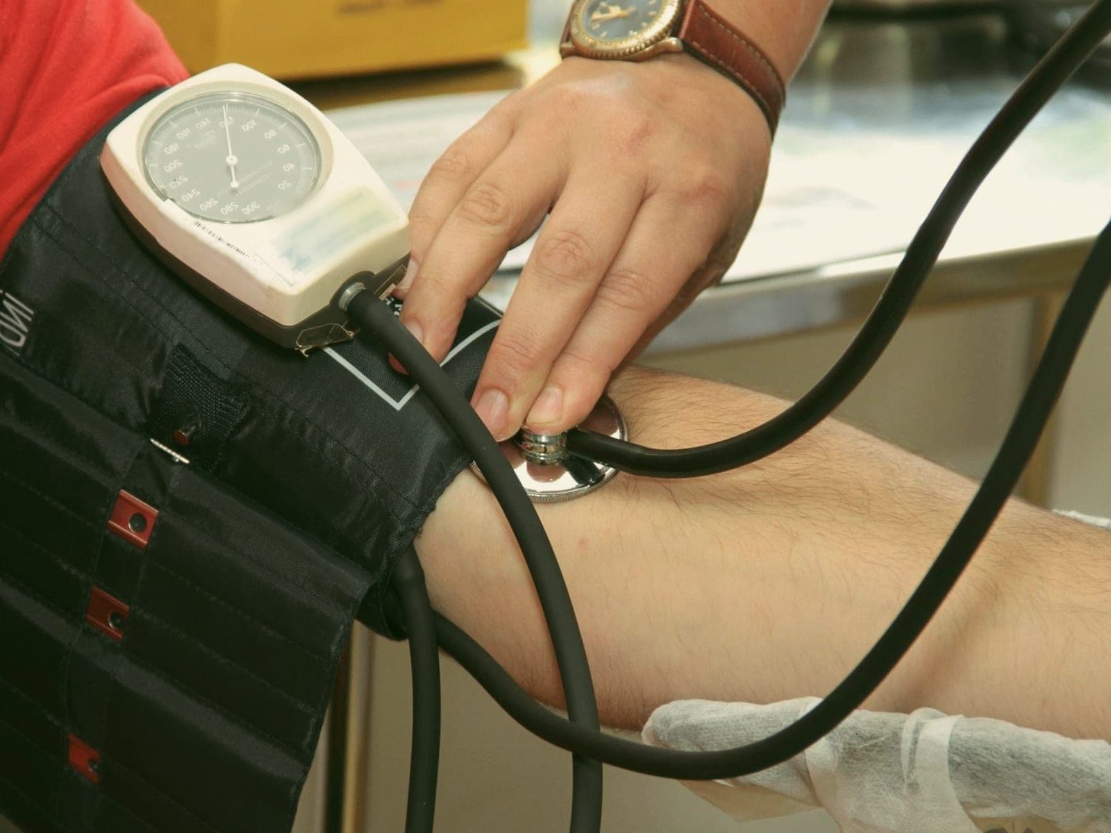 A clinician taking a blood pressure reading with a cuff and stethoscope